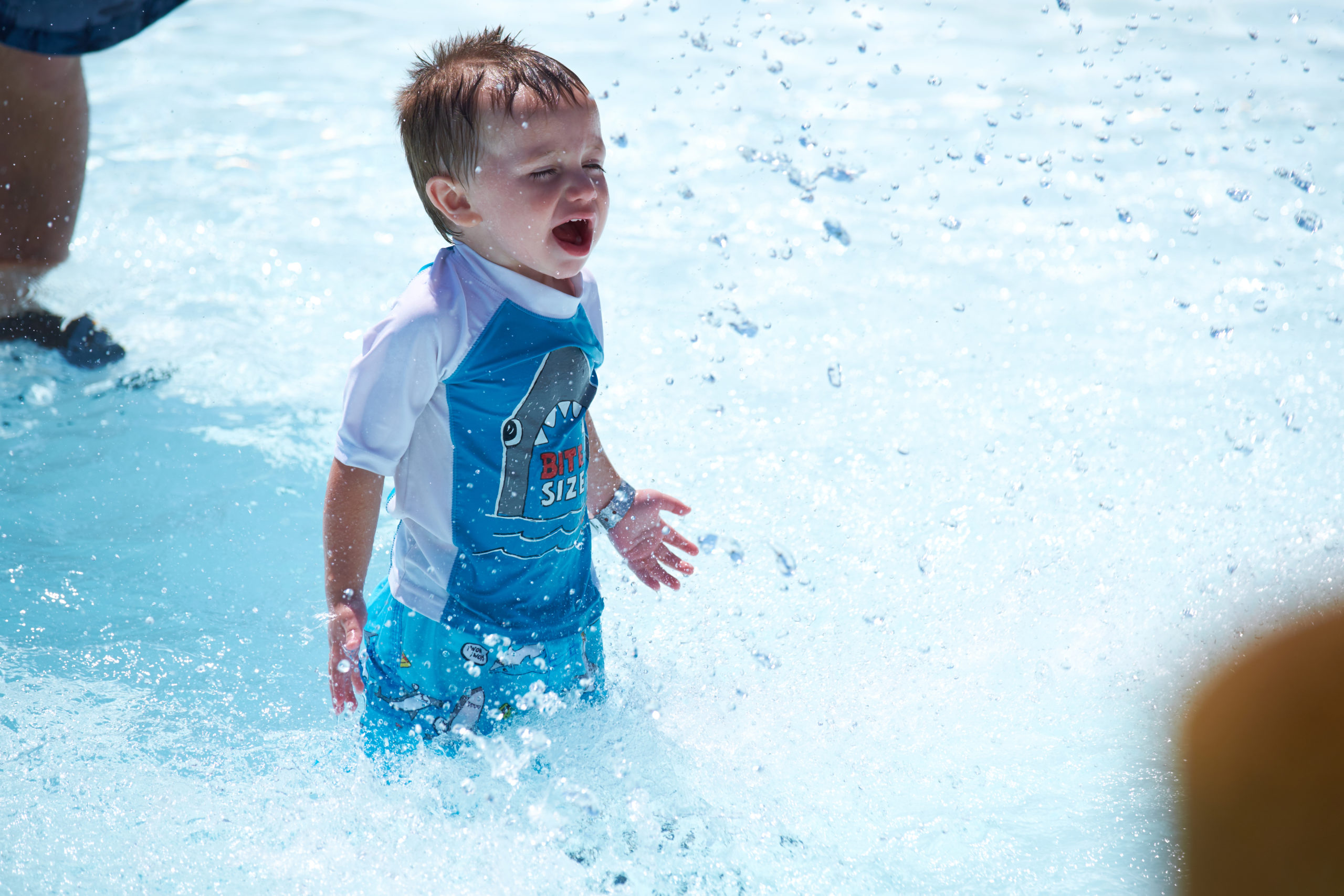 A young boy smiles in a pool.