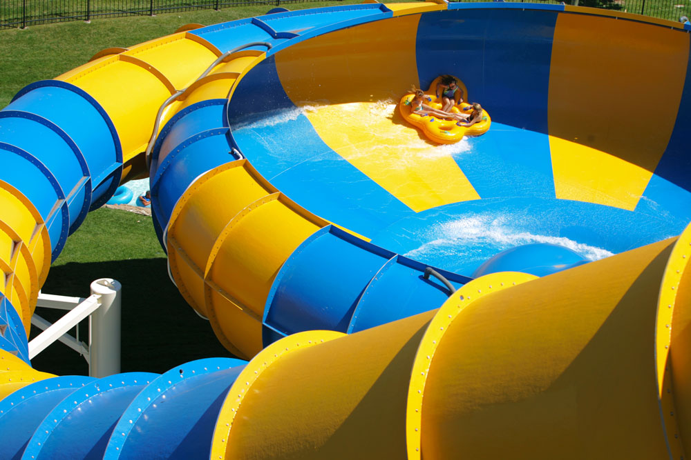 Three girls sliding on water tube at The Revolution, Water World